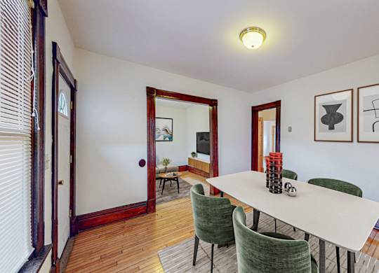A dining room with a white table and green chairs.
