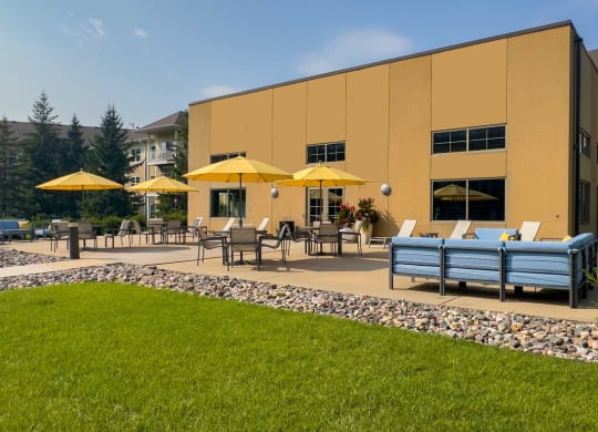 an outdoor patio with tables and umbrellas at chaska place apartments in chaska mn