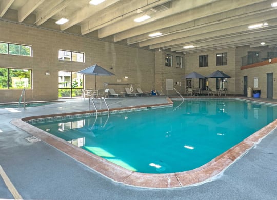 an indoor pool with tables and umbrellas