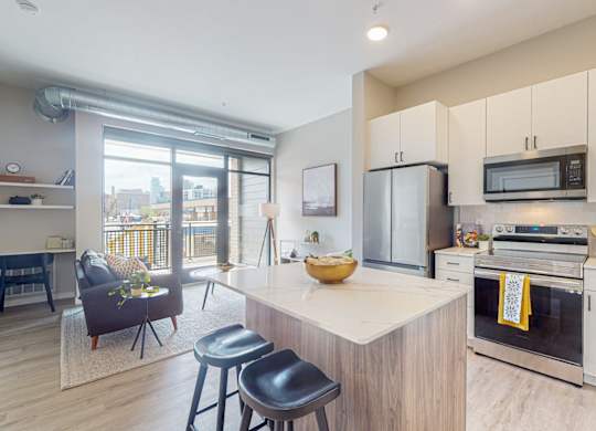 a kitchen with white cabinets and a large island with a marble countertop