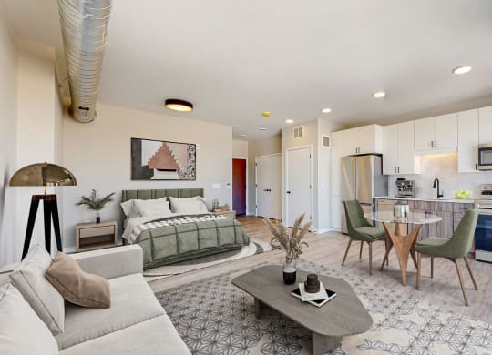 a living room with a bed and a kitchen in the background