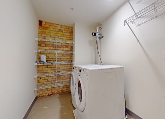 a washer and dryer in a laundry room with a brick wall
