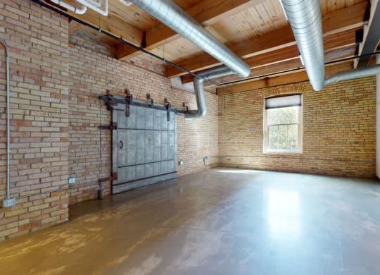 a large empty room with brick walls and a large window