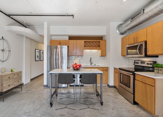 a kitchen with a stainless steel refrigerator and a table with chairs