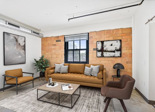 a living room with a couch and a coffee table and a brick wall