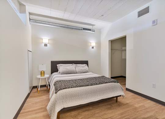 A bedroom with a bed, nightstand, and a lamp.