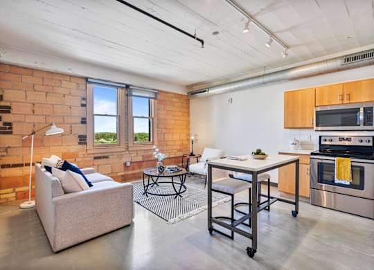 A living room with a couch, a table, and a brick wall.