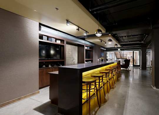 A long bar with stools is in the middle of a room.