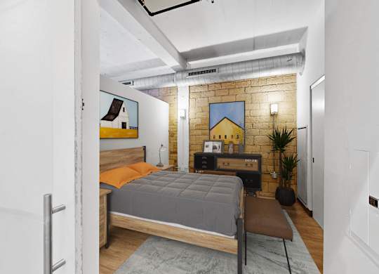 A bedroom with a bed, a chair, and a plant.