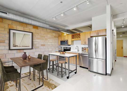A kitchen with a table and chairs in front of a brick wall.