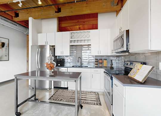 A kitchen with white cabinets and a wooden ceiling.