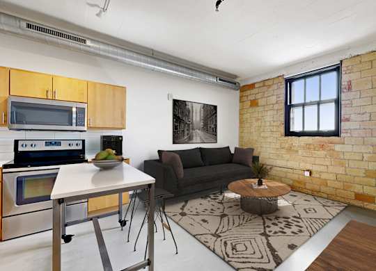 A kitchen with a brick wall and a table with a bowl of fruit on it.