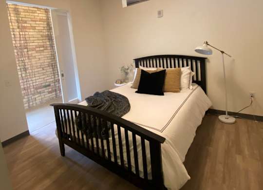 A bedroom with a bed, wooden headboard, and a white bedspread.