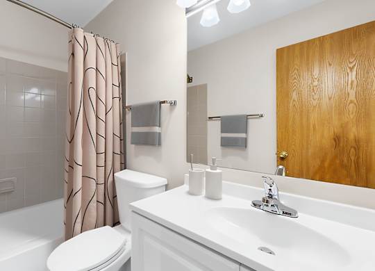 A white bathroom with a toilet, sink, and shower.