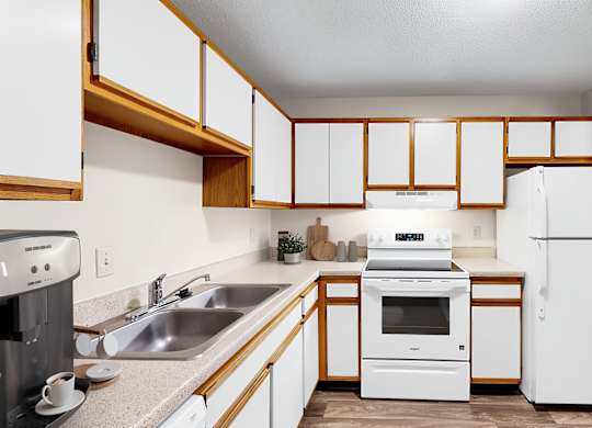 A kitchen with white appliances and wooden cabinets.