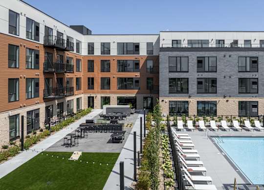 A modern building with a pool and lounge chairs.