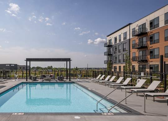 A swimming pool surrounded by lounge chairs and umbrellas.
