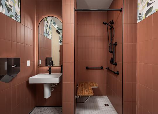 A bathroom with a sink, mirror, and shower.