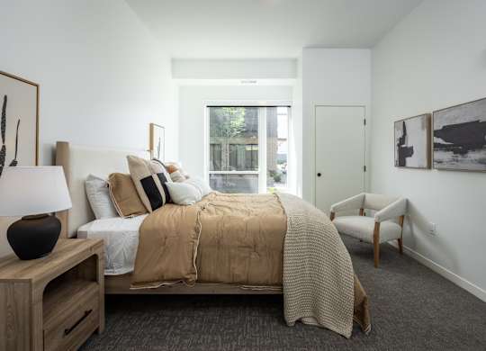A bedroom with a bed, chair, and pictures on the wall.