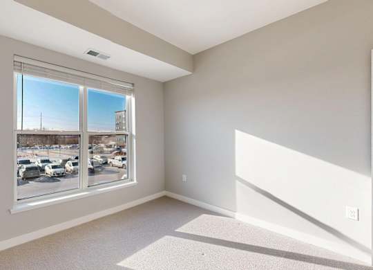 A room with a large window overlooking a parking lot.