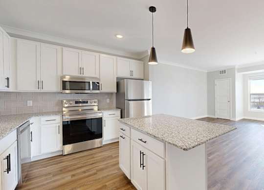 A kitchen with white cabinets and a granite countertop.