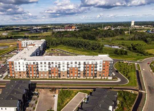 A large building with a parking lot in front of it. at The Edison at Maple Grove, Maple Grove