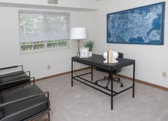 a room with a desk and chair and a large blue map on the wall