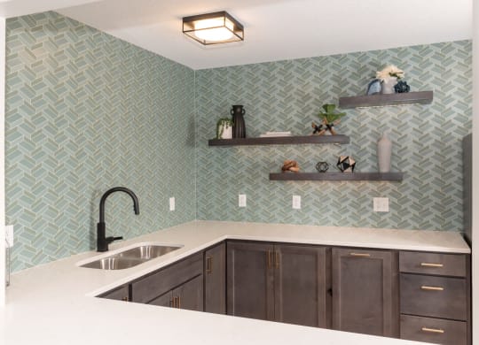 a kitchen with green tile and white countertops