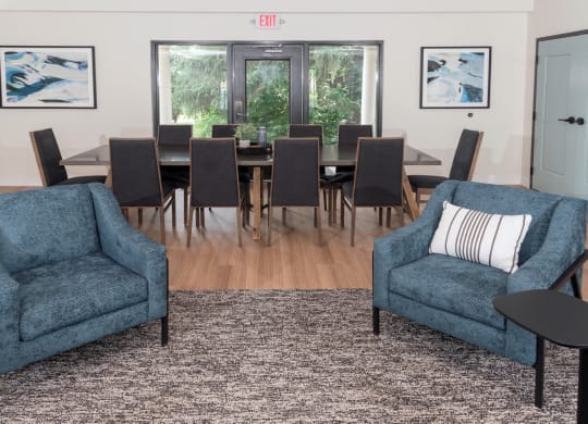 a living room with two blue chairs and a large dining table