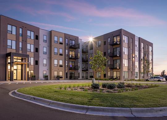 A modern apartment building with a well-maintained lawn in front.