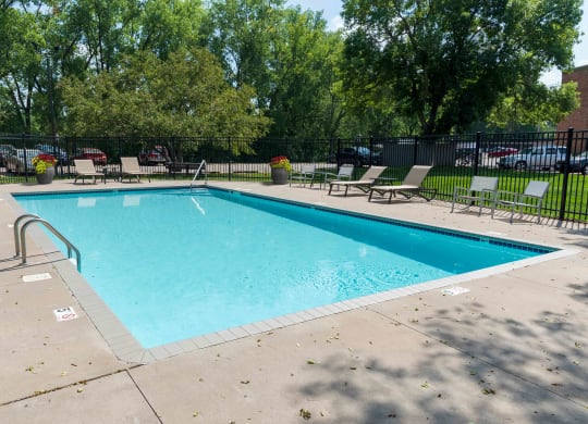 a swimming pool with lounge chairs and trees in the background