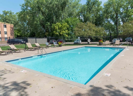 a swimming pool with chaise lounge chairs and trees in the background