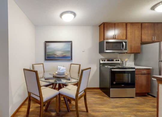 a dining area with a table and chairs and a kitchen in the background