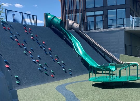 a green slide on the side of a building with a blue sky in the background