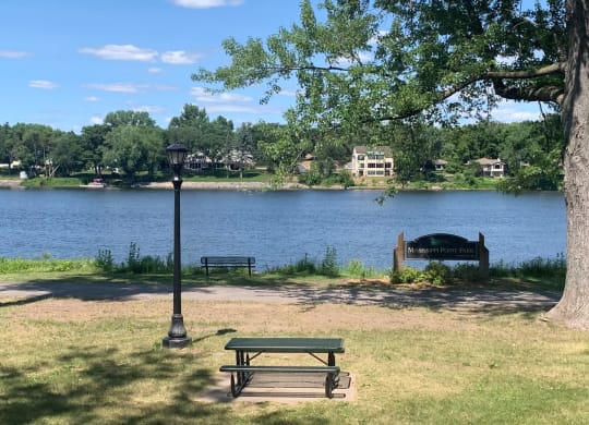 a picnic area with a bench next to a lamp post and a lake in the background