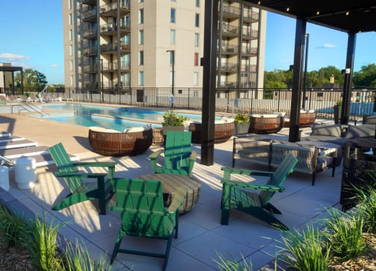 a pool area with lounge chairs and tables and a building in the background