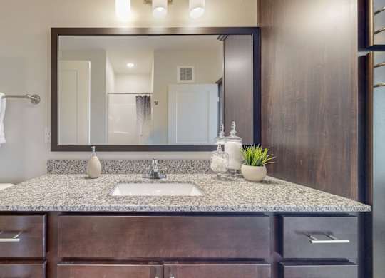A bathroom with a granite countertop and a large mirror. at Lake Jonathan Flats, Chaska, MN, 55318