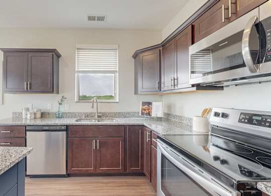 A kitchen with a granite countertop and stainless steel appliances. at Lake Jonathan Flats, Chaska, Minnesota