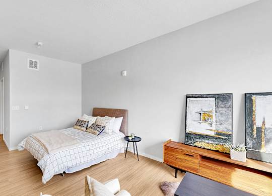 A bedroom with a bed, a nightstand, a chair, and a painting on the wall.