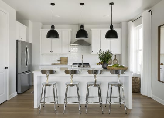a kitchen with white cabinets and a white island with bar stools