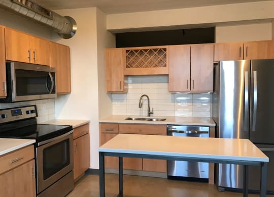 Open Kitchen with Wooden Cabinetry, Stainless Steal Appliances and White Counter Tops at Minneapolis Apartment