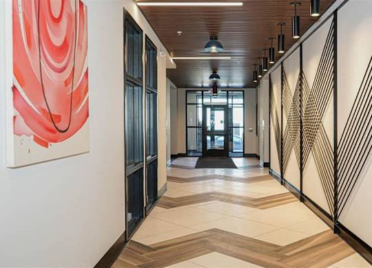 A hallway with a red and black abstract painting on the wall at The Bessemer at Seward Commons Apartments, Minneapolis, 55404