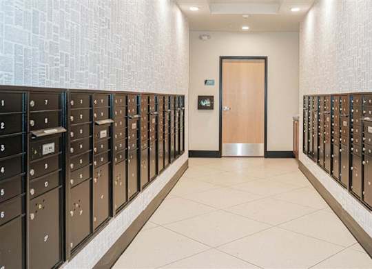A hallway with a row of lockers on both sides and a door at the end at The Bessemer at Seward Commons Apartments, Minneapolis