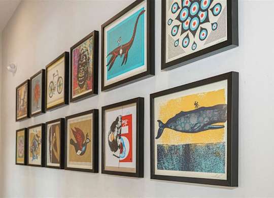 A wall with framed pictures of animals and patterns at The Bessemer at Seward Commons Apartments, Minnesota, 55404