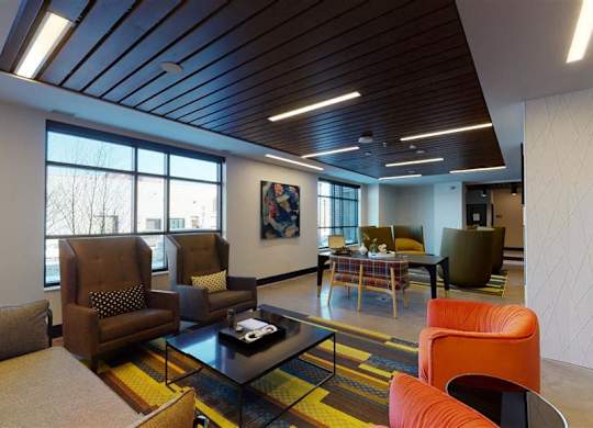 A modern living room with a wooden ceiling and a large window at The Bessemer at Seward Commons Apartments, Minneapolis, MN,  55404