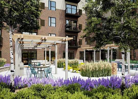 A building with a patio and a white pergola at The Bessemer at Seward Commons Apartments, Minneapolis