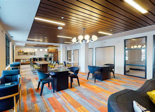 A room with a long table and chairs with a carpet on the floor at The Bessemer at Seward Commons Apartments, Minneapolis, 55404