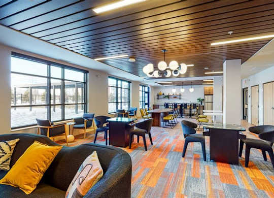 A modern office space with a variety of seating options and a colorful carpet at The Bessemer at Seward Commons Apartments, Minneapolis, MN,  55404