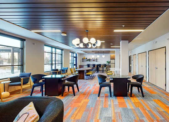 A large room with a long table and chairs at The Bessemer at Seward Commons Apartments, MN, 55404