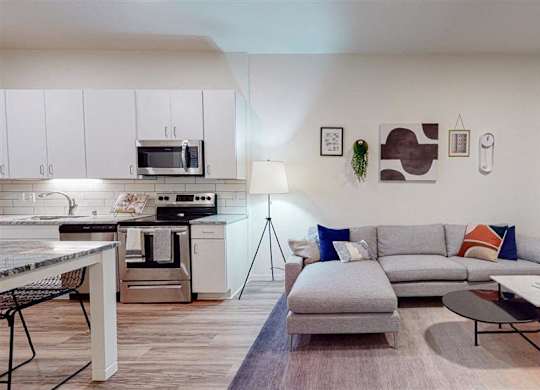 A modern kitchen with a grey sofa and a coffee table at The Bessemer at Seward Commons Apartments, Minneapolis, MN,  55404